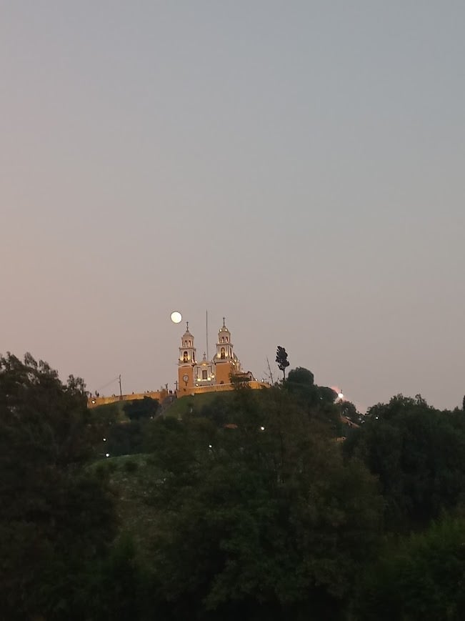 Golden-domed cathedral illuminated at dusk on a forested hilltop in Puebla Mexico - UNESCO heritage colonial architecture