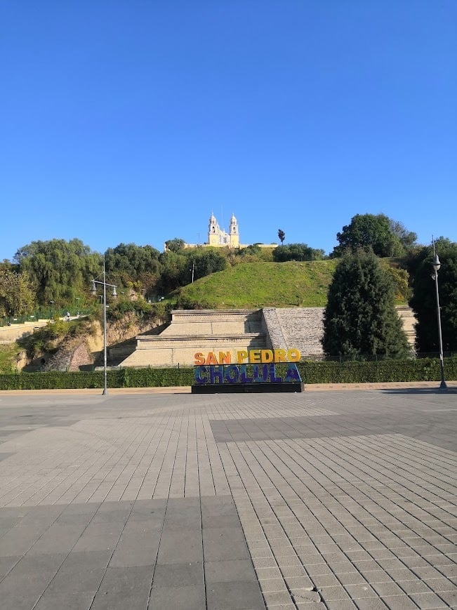 San Diego sign in foreground with green hillside and white church building atop hill under blue sky