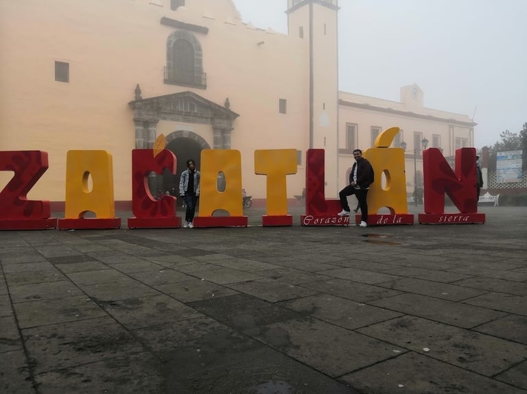 Colorful ZACATLAN letters in town plaza with colonial church in background